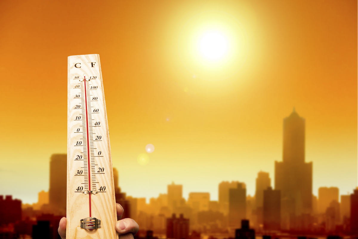 heatwave in the city and hand showing thermometer